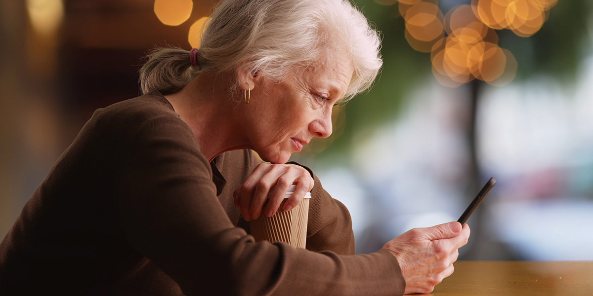 Side portrait of old woman reading concerning text on smartphone at cafe Nur wenige Mitglieder sind Fans